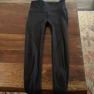 Black lulu lemon leggings with cutouts throughout the pant.